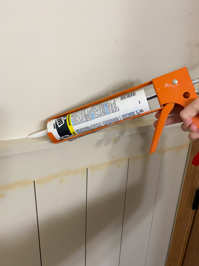 Caulking a line on top of faux shiplap wall