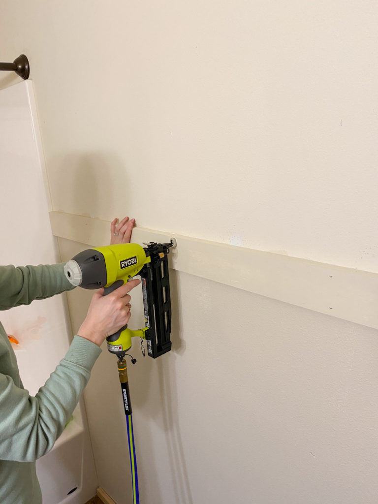 Using a nail gun to secure shiplap to the wall