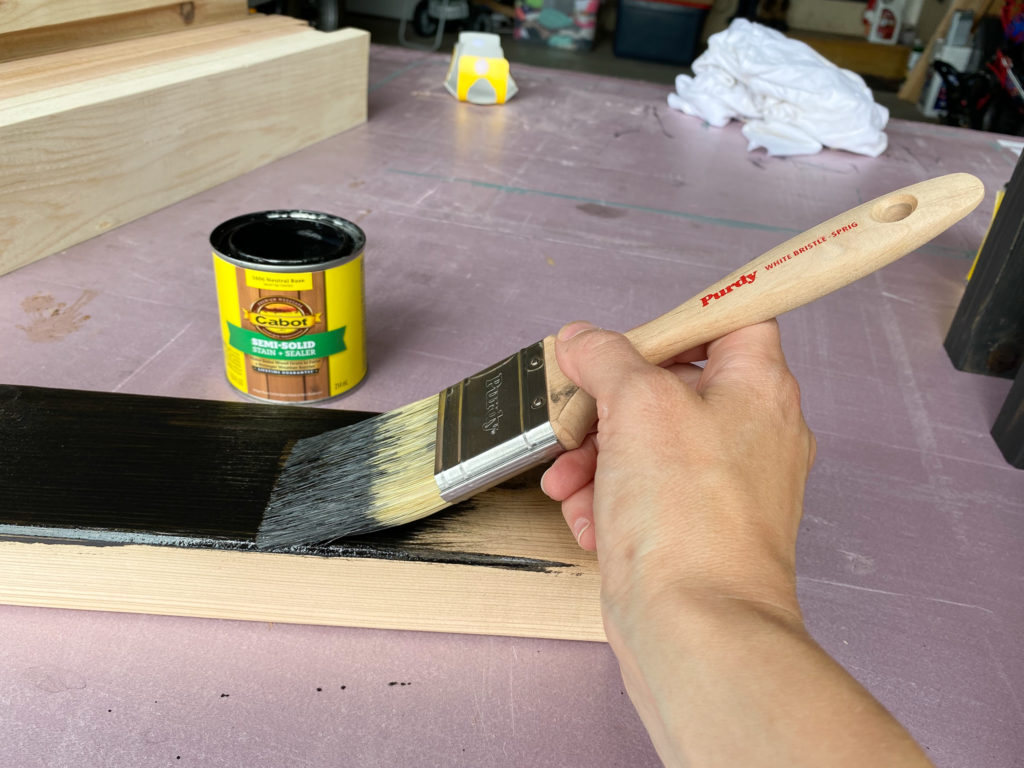 Applying black Cabot stain to boards for bench